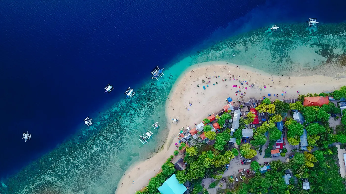 Reef, white sand and outrigger boats off Mactan Island, Cebu